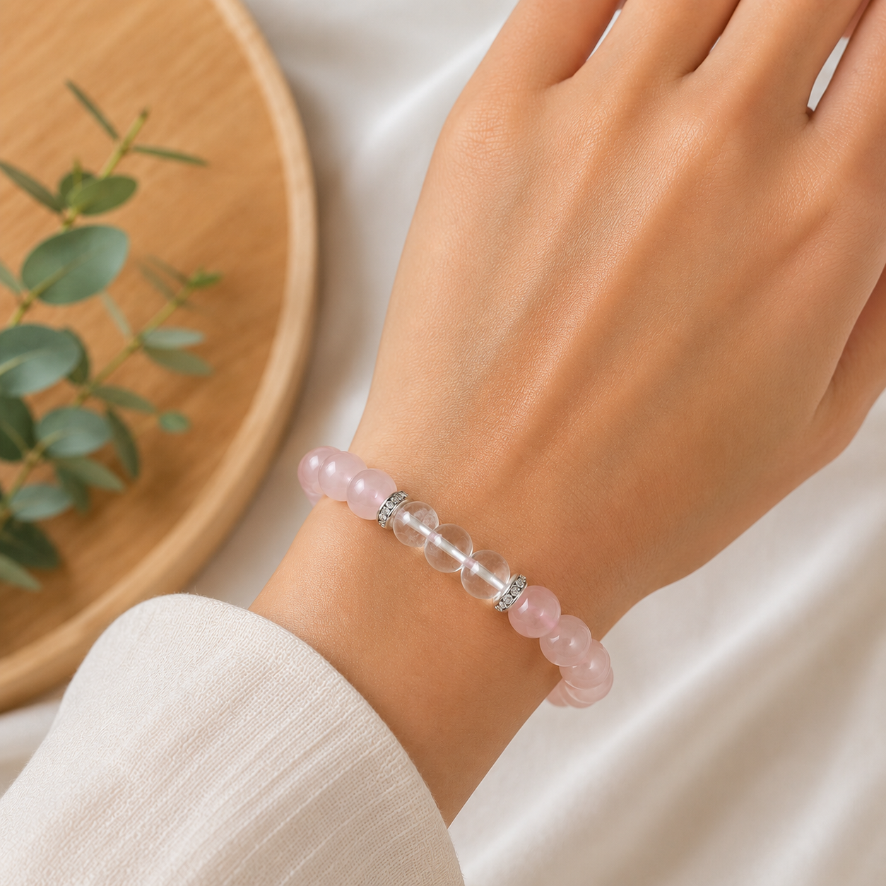 Handgefertigtes Armband aus natürlichem Rosenquarz und Bergkristall mit silberfarbenen Zirkonia-Zwischenringen auf elastischem Band.